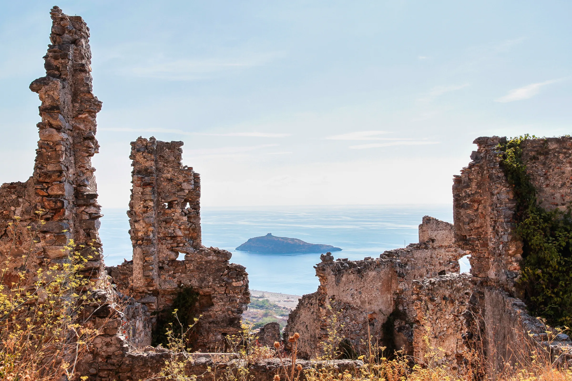 L'Isola di Dino vista attraverso i ruderi in pietra sulla collina